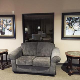 A cozy living room setting with a gray sofa flanked by two wooden side tables and framed artwork on the walls.
