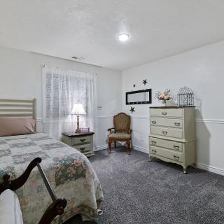 A cozy bedroom with a classic design featuring a bed, dresser, and chair.