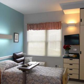 A hospital room featuring a single bed, a television, and standard medical furnishings.