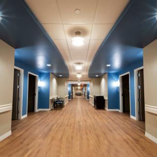A well-lit hallway in a modern building with wooden flooring and multiple doors.