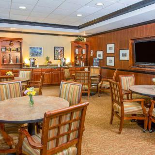A well-furnished lounge area with tables and chairs, featuring warm lighting and decor.