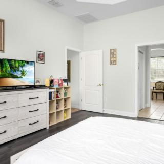 A modern bedroom with a dresser, television, and white walls.