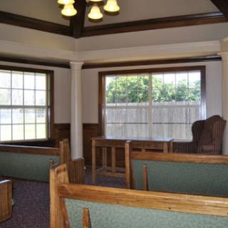 A cozy interior space featuring wooden furniture, ample seating, and natural light streaming through the windows.