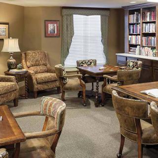 A cozy living room with comfortable seating, tables, and a bookshelf.