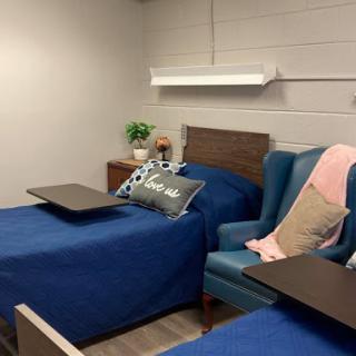 A well-designed hospital room featuring two beds, comfortable chairs, and a calming color palette.