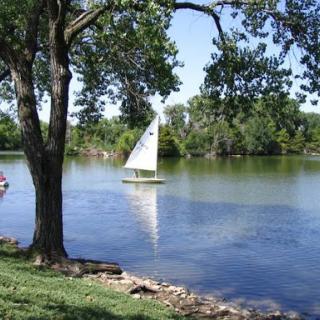 A serene afternoon on the lake with a sailboat gliding across the water.