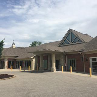 A modern architectural building with a welcoming entrance under a cloudy sky.