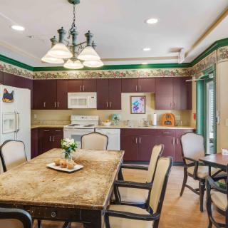 A cozy kitchen and dining area with a large table, chairs, wooden cabinets, and decorative lighting.