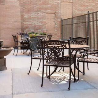 A serene outdoor patio featuring elegant metal furniture and a decorative fountain.
