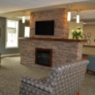 A modern living room with a central stone fireplace, TV, and comfortable seating.