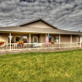 A charming house with a welcoming porch and a vibrant garden under a cloudy sky.
