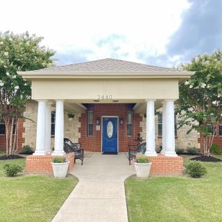 A charming house entrance with columns, a blue door, and landscaped front yard.