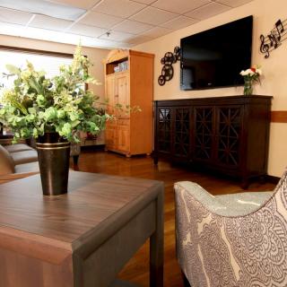 A cozy living room setup with modern furniture, a large television, and decorative plants.