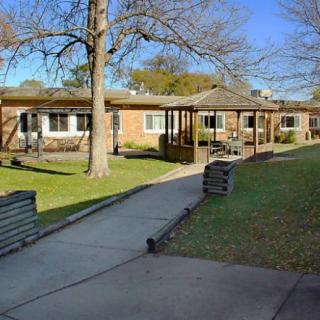 A sunny day view of a building with a covered walkway and surrounding trees.