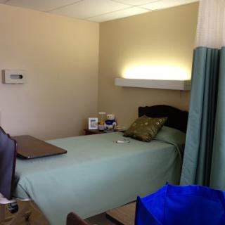 A clean and organized hospital room featuring a bed, bedside table, and essential medical equipment.