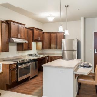 A modern kitchen featuring wood cabinets, stainless steel appliances, and an open layout.