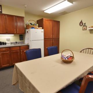 A cozy kitchen and dining area with a table, chairs, refrigerator, and wooden cabinets.