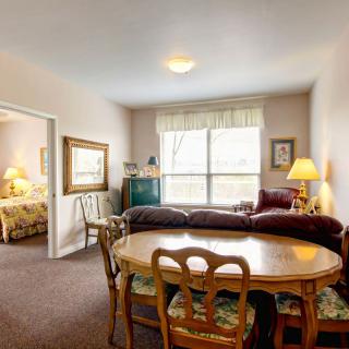 A cozy living room with a dining area featuring classic furniture and soft lighting.