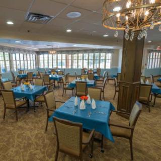 A spacious dining area with blue tablecloths and elegant lighting.