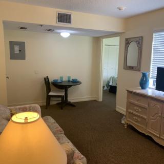 A cozy living room with a table, chairs, dresser, and a wall mirror.