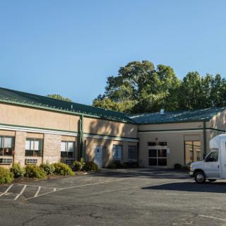 A commercial building with a green roof and a parking lot, featuring a delivery vehicle.