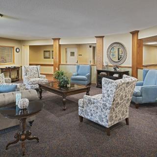 A cozy living room with a variety of armchairs and a central coffee table, decorated in neutral tones.