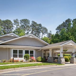 A single-story residential building with a landscaped entrance and surrounding trees.