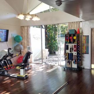 A bright and spacious home gym with various exercise equipment arranged neatly.