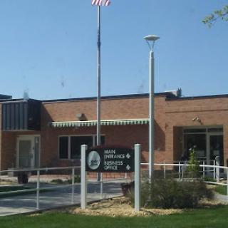 An exterior view of a public building with an American flag and signage.