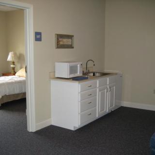 A small kitchenette area with a microwave and sink adjacent to a bedroom.