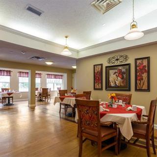 A cozy and elegantly designed dining area with neatly arranged tables and chairs, complemented by tasteful wall decor.