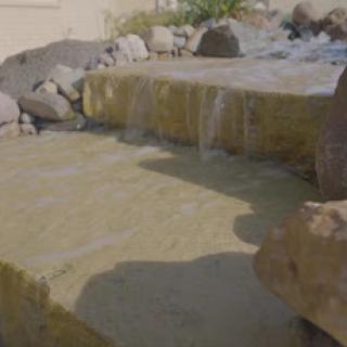 A serene waterfall cascading over natural stones, creating a peaceful outdoor ambiance.