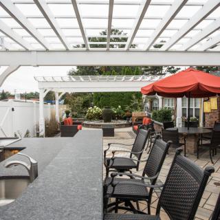 A stylish outdoor patio area with a pergola, bar seating, and umbrellas.
