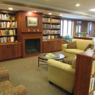 A cozy library with bookshelves, a fireplace, and comfortable seating.