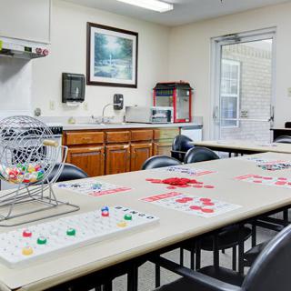 A cozy game room set up for bingo, featuring tables and chairs, a kitchenette, and organized bingo supplies.