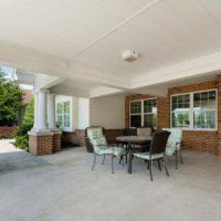 Covered patio area with a table and chairs next to a brick wall.