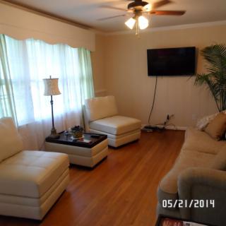 A cozy living room with a sofa, chairs, and a wall-mounted TV.