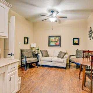 A cozy living room with a sofa, chairs, and a small dining area, featuring wooden flooring and decorative artwork.