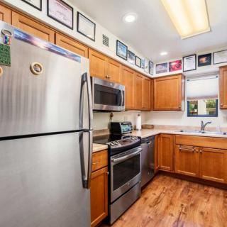 A modern kitchen with stainless steel appliances and wooden cabinets, decorated with framed pictures on the walls.