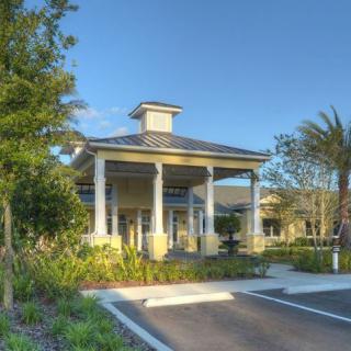 A well-maintained building entrance with columns and surrounding greenery under a clear blue sky.