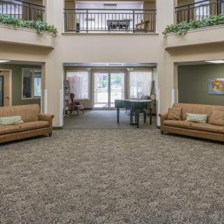 A spacious lobby area with sofas, carpeted flooring, and indoor balconies.