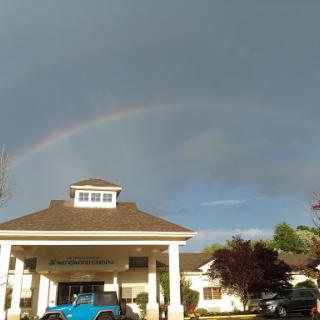 A beautiful rainbow arches over a building, contrasting against the dark sky.