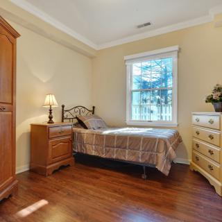 A cozy bedroom with a single bed, wooden furniture, and a window letting in natural light.