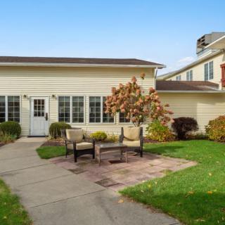 A cozy outdoor patio area with chairs set in front of a residential building.