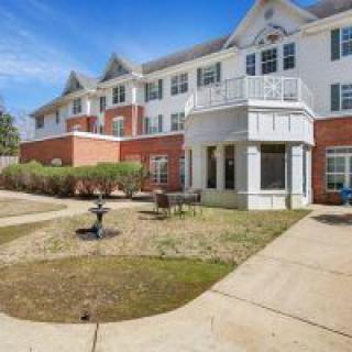 A large residential building with a garden and walkway under a clear blue sky.