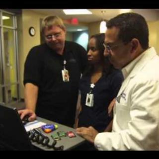 Medical professionals collaborate while examining information on a device in a hospital setting.