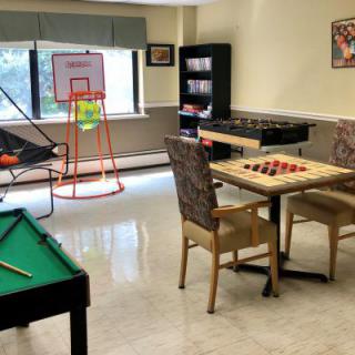 A game room featuring a pool table, checkers board, basketball hoop, and foosball table.