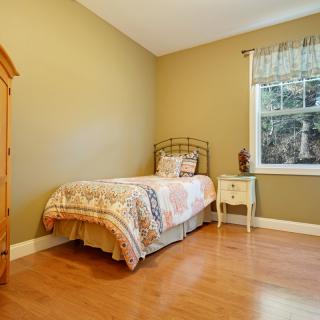 A cozy single bedroom with wooden flooring and simple furnishings.