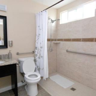 A modern bathroom with a shower and toilet featuring grab bars for accessibility.