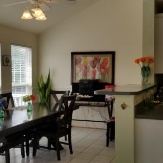 A cozy dining area with a table, chairs, and decorative elements like artwork and plants.